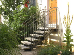 Außentreppe mit Natursteinstufen und genietetem Geländer